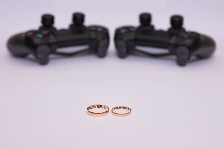 SAINT-PETERSBURG â RUSSIA - SEPTEMBER 27 2019: Wedding rings with engraved text player 1 player 2 and Dualshock 4 controllers for Sony PlayStation 4 lies on white background. Close-up, shallow depth of fieldのeditorial素材