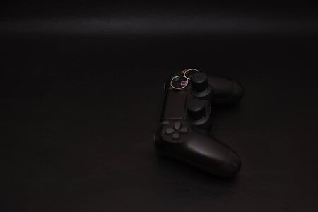 SAINT-PETERSBURG â RUSSIA - SEPTEMBER 27 2019: Wedding rings with engraved text player 1 player 2 on Dualshock 4 controller for Sony PlayStation 4 on black background. Close-up, shallow depth of fieldのeditorial素材