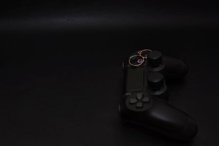 SAINT-PETERSBURG â RUSSIA - SEPTEMBER 27 2019: Wedding rings with engraved text player 1 player 2 on Dualshock 4 controller for Sony PlayStation 4 on black background. Close-up, shallow depth of fieldのeditorial素材