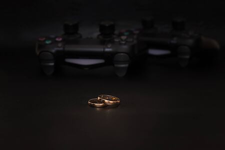 SAINT-PETERSBURG â RUSSIA - SEPTEMBER 27 2019: Wedding rings with engraved text player 1 player 2 and Dualshock 4 controllers for Sony PlayStation 4 lies on black background. Close-up, shallow depth of fieldのeditorial素材