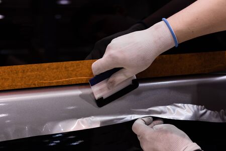 specialist pasting car with vinyl film. Close-up shallow depth of field.