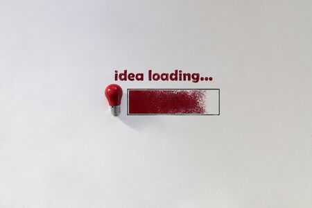 Small red light bulb top view on white background. Chalk inscription Idea loading and drawn loading bar. Concept thought arising. Top view picture with copy spaceの写真素材