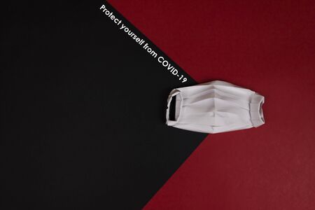 Origami paper medical protective mask flat lay with copy space. Chalk inscription Protect yourself from COVID-19. Call for Coronavirus protection concept.の写真素材