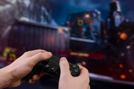 SAINT-PETERSBURG, RUSSIA, MARCH 20 2020: Man playing a shooter video game. Gamepad in hands. Stay...
