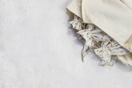 Three eco sack with drawstring inside of shopping bag made from natural cotton fabric cloth. Flat lay on white background. Plastic free set, reusable bags. Zero waste concept. Copy spaceの写真素材