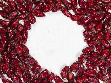 Round frame made of dried rose hips on white background. Picture with copy space and selective focus. Healthy eating concept. の写真素材