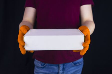 Parcel delivery during quarantine of covid-19. Delivery man wearing protective gloves holds white...