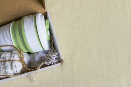 Eco-friendly shipping. Delivery of box with collapsible silicone mug, mesh bag and reusable cotton discs set for face or makeup removal tied with twine. Zero waste concept. Online shoppingの写真素材