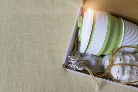 Eco-friendly shipping. Delivery of box with collapsible silicone mug, mesh bag and reusable cotton discs set for face or makeup removal tied with twine. Zero waste concept. Online shoppingの写真素材