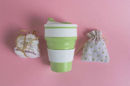 Collapsible silicone mug, mesh bag and reusable cotton discs set for face or makeup removal tied with twine. Zero waste concept top view on pink background. Eco-friendly lifestyleの写真素材