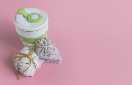 Collapsible silicone mug, mesh bag and reusable cotton discs set for face or makeup removal tied with twine. Zero waste concept top view on pink background with copyspace. Eco-friendly lifestyleの写真素材