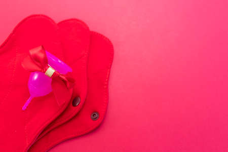 Menstrual cup and Reusable Menstrual Pad as a gift, flat lay on pink background. Zero waste concept. Caring for the environment. Women Health. Picture with place for textの写真素材