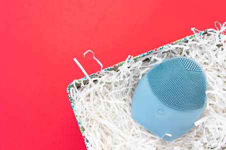 Silicone brush for washing face in shredded paper packaging material. Facial cleansing brush as gift. Skincare concept. Brush for face lifting, anti-aging wrinkles and massage. Copy spaceの写真素材