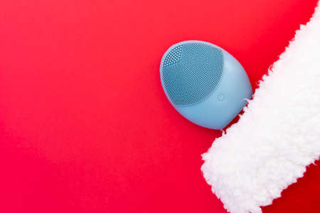 Silicone brush for washing face and a Christmas hat. Facial cleansing brush as gift. Skincare concept. Brush for face lifting, anti-aging wrinkles and massage. Copy spaceの写真素材