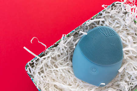 Silicone brush for washing face in shredded paper packaging material. Facial cleansing brush as gift. Skincare concept. Brush for face lifting, anti-aging wrinkles and massage. Copy spaceの写真素材