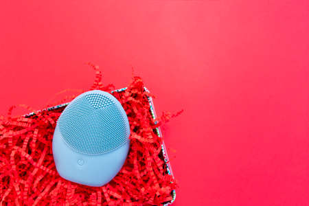 Silicone brush for washing face in shredded paper packaging material. Facial cleansing brush as gift. Skincare concept. Brush for face lifting, anti-aging wrinkles and massage. Copy spaceの写真素材