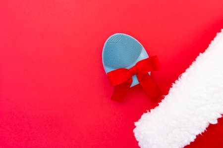 Silicone brush for washing face and a Christmas hat. Facial cleansing brush as gift. Skincare concept. Brush for face lifting, anti-aging wrinkles and massage. Copy spaceの写真素材