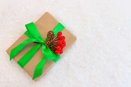 Gift wrapped in craft paper and decorated with green and red ribbons flat lay with snow on background. Top view picture with place for text and shallow depth of fieldの写真素材