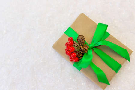 Gift wrapped in craft paper and decorated with green and red ribbons flat lay with snow on background. Top view picture with place for text and shallow depth of fieldの写真素材