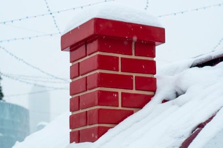 Red smoke brick pipe, chimney close-up, on the roof of a snow-covered house. Symbol of the New Year holidays, Christmas and the arrival of Santa Claus. Snowdrifts on the roof withの写真素材
