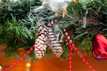 Cones close-up, against the background of green branches, decorated with festive garlands. The concept of winter New Year holidays.の写真素材
