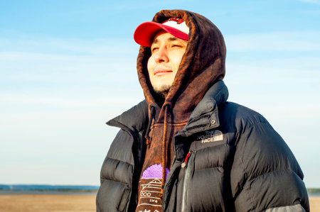 Moscow, Russia - March 9, 2022: A young guy, in the north face clothes, stands in nature, on a sunny cold autumn day.のeditorial素材