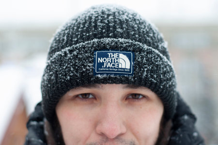 Moscow, Russia - March 01, 2022: A man in a black winter hat from The North Face clothing company in winter. Close-up of the logo on the clothes.のeditorial素材