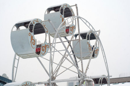 Russian attraction "Ferris wheel" on the street in winter. Cabins of an attraction, a rotating wheel. Ferris wheel in Russia. Winter entertainment for the New Year holidays. big wheel winterの写真素材