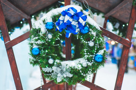 Christmas wreath close-up, outdoors in winter, covered with snow. Green spruce wreath with blue balls and decorations.の写真素材