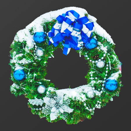 Christmas wreath made of naturalistic looking pine branches decorated with blue balls, ribbon, isolated on black background.の写真素材