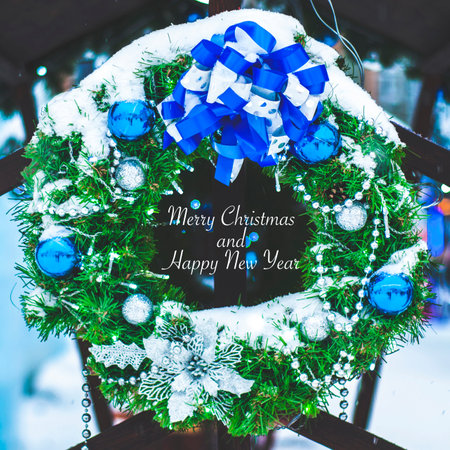 Christmas wreath made of naturalistic looking pine branches decorated with blue balls, ribbon, with the inscription text : "Merry Christmas and Happy New Year"の写真素材