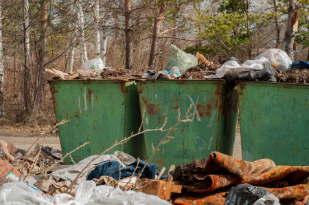 Large, old, rusty metal trash cans. Street trash cans, against the backdrop of a green forest and trees.の写真素材