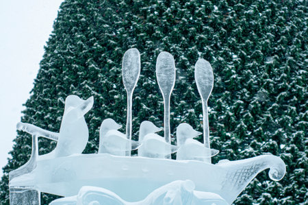 Figure of penguins in a boat, carved from ice. An ice figure in the city square against the backdrop of a Christmas tree, in honor of the Christmas holidays. Street decoration of the city.の写真素材