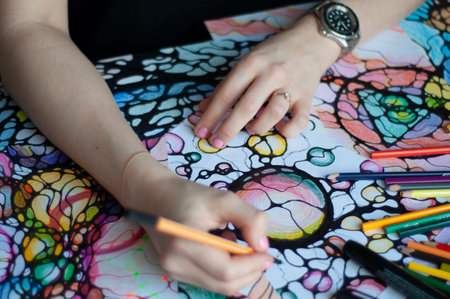 Close-up of female hands drawing neurographic art. Mental health, adult fine motor skills, creativity, psychology. Abstract neurographic drawing with a marker, colored pencils. Art. selective focus.の写真素材