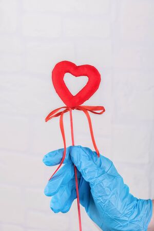 Female hand in blue medical gloves holding a red heart, symbol of life. Thank you nurses and doctors. Concept support of people infected of coronavirus, protect the world and Earth from covid-19の写真素材