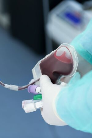 The hand of male donor gives blood in a mobile blood donation center. Blood samples. Hands of the nurse with protective gloves. Donation to support during a pandemia of coronavirus, selective focusの写真素材