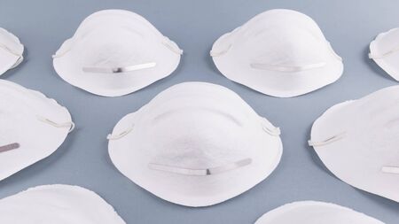 Pattern of white face medical mask on a grey background. Health care and coronavirus prevention concept. Face mask protection against pollution, virus, flu and infectionsの写真素材