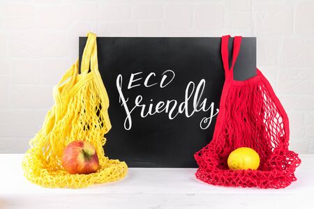 lettering eco friendly, message on a black chalkboard and two string mesh cotton bags with apple and lemon, use eco packeging in your kitchen, zero waste conceptの写真素材