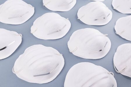 Pattern of white face medical mask on a grey background. Health care and coronavirus prevention concept. Face mask protection against pollution, virus, flu and infectionsの写真素材