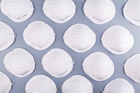 Pattern of white face medical mask on a grey background. Health care and coronavirus prevention concept. Face mask protection against pollution, virus, flu and infections. Pandemiaの写真素材