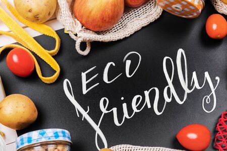lettering eco friendly, message on a black chalkboard and vegetables in a cotton eco sacs, string mesh bag and glass jar with legume, use eco packeging in the kitchenの写真素材