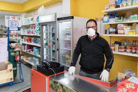 Avetrana, Italy, - Marth 16, 2020. Saleseman wearing in gloves and medical mask, Respecting health standards during the epidemy of Coronavirus, quarantine covid-19, selective focusのeditorial素材