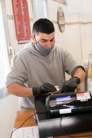 Avetrana, Italy, - Marth 19, 2020. A cashier is a working in medical mask and gloves during pandemia of coronavirus, quarantine covid-19, selective focusのeditorial素材
