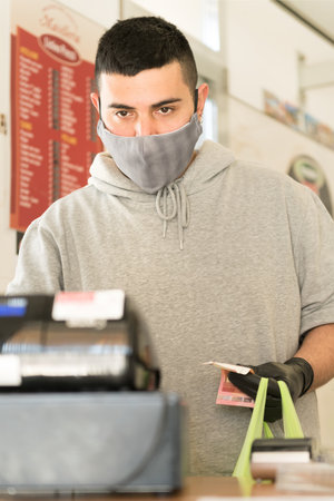 Avetrana, Italy, - Marth 19, 2020. A cashier is a working in medical mask and gloves during pandemia of coronavirus, quarantine covid-19, selective focusのeditorial素材