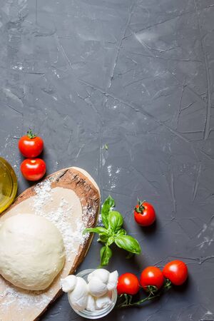 Raw ingredients for pizza on the chalkboard with copy space, dough, tomatoes, mozzarella, basil, vertical photoの写真素材