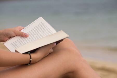 Girl reading a book on the beach, reading on the beach, vacation concept, summer timeの写真素材