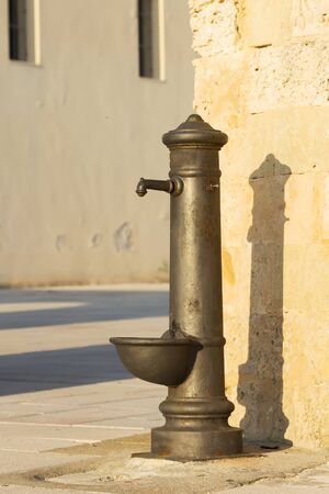 Typical drinking fountain in the south of Italy, Salento, Puglia, drinking water outside in bright sunny afternoonの写真素材