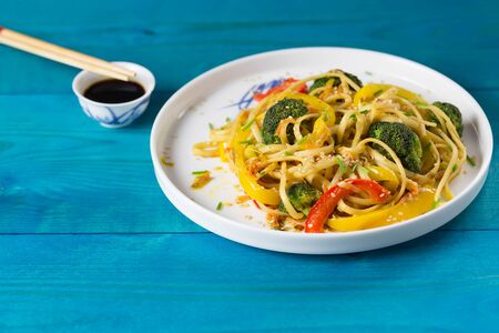 Asia food. Stir fry udon noodles with vegetables on a blue wooden backgound, cooked in wokの写真素材
