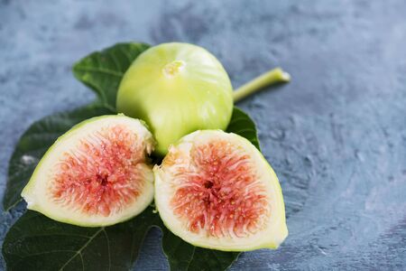 Ripe sweet green figs with green leaves. Healthy mediterranean fig fruit on a blue wooden background, made in Puglia, Italy selective focusの写真素材