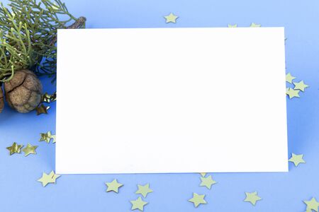 Christmas card mockup, festive background with christmas golden stars, top view. Christmas decoration on a pastel blue backgound, minimal composition, festive layout, space for textの写真素材